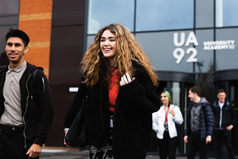 Students smiling and walking outside of a building